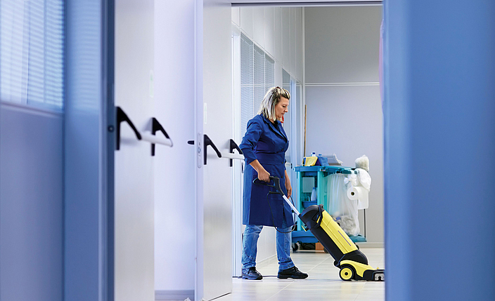 Gebäudereinigerin arbeitet alleine mit einer Reinigungsmaschine.
    