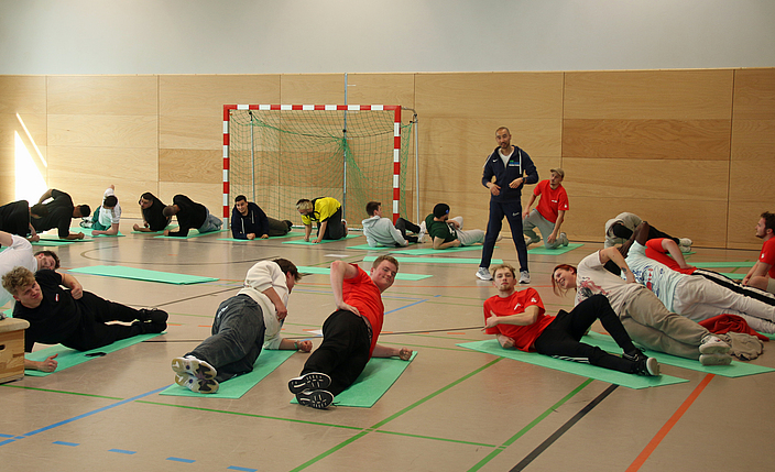 Auszubildende trainieren in einer Turnhalle.
    
