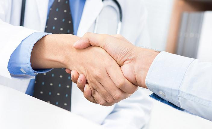 Detailansicht: Arzt und Patient schütteln sich die Hände.
    